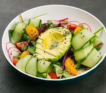 Зеленый салат с половинкой авокадо, семенами чиа и тыквой