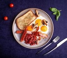 Английский завтрак с куриными колбасками, беконом, фасолью, томатами и шампиньонами