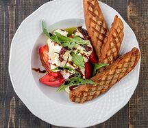 Молодой сыр на розовых томатах с рукколой и хрустящими тостами 