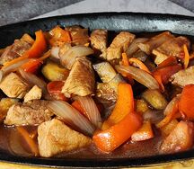 Шипящая сковородка со свининой и овощами в остром соусе