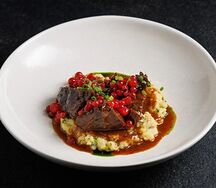 Томленая щека теленка с толчёным картофелем, мочёной брусникой и соусом демиглас