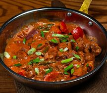 Горячая сковорода со свининой и овощами в соусе из свежих томатов