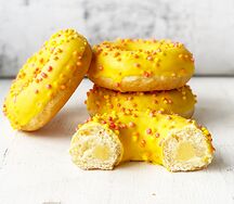 Донат с начинкой манго, желтой глазурью и цветной посыпкой