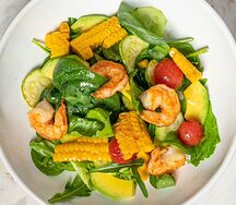 Салат с обжаренными креветками, цукини и кукурузой на гриле, огурцом, авокадо и черри