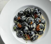 Черные пельмени с судаком, красной икрой и соусом белое вино