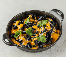 Черные пельмени с тигровыми креветками в бульоне Том Ям