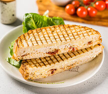 Сэндвич с индейкой, тянущимся сыром моцарелла, вялеными томатами и домашней заправкой цезарь