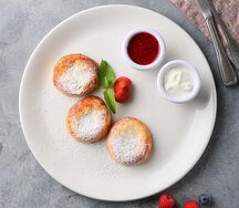 Фирменные сырники от АндерСон из свежего творога с протертой малиной и сметаной