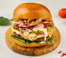 Бургер с двойной котлетой, жареным беконом, маринованным огурцом, красным луком и томатами