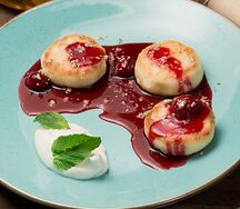 Сырники со сметаной, вишневым соусом и халвой