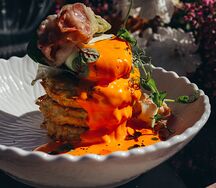 Драники с соусом чеддер, беконом и яйцом пашот