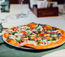 Пицца с пастрами, вялеными томатами, страчателлой и рукколой