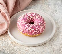 Донат с розовой глазурью и посыпкой из белого шоколада