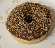 Пончик донатс с ореховой начинкой, ореховой глазурью с дробленым арахисом