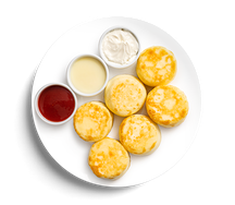 Большая порция сырников со сметаной и клубничным соусом