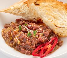 Тартар из говядины с яйцом, маринованным огурцом и имбирно-лаймовой заправкой  