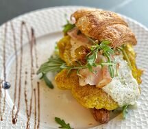 Круассан с картофельным драником, беконом и соусом трюфель