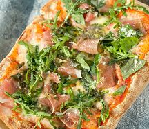 Фирменная пицца Gastrobar с прошутто, рукколой, моцареллой, пармезаном и соусом Песто