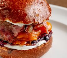 Бургер с котлетой из мраморной говядины и копченой грудинки с маринованным луком