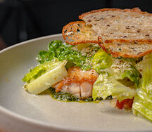 Салат с цыпленком, обжаренным до золотой корочки, хрустящими гренками, томатами черри и сыром пармезан