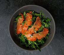 Салат с рукколой, красной рыбой слабой соли и свежими огурчиками под соусом песто