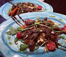 Руккола с мраморной говядиной овощами и орехами