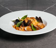 Спагетти с морепродуктами в томатном соусе со свежими листьями базилика