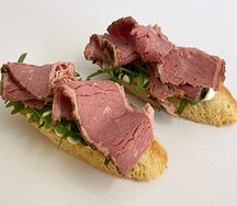 Мини-брускетты с пастрами из говядины, сливочным соусом и рукколой