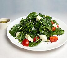 Салат с моцареллой и томатами черри на подушке из зелени