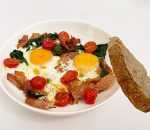 Яичница с беконом, томатами черри и шпинатом, с ломтиком хлеба тартин