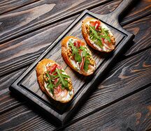 Брускетта с ветчиной, сыром дорблю, руколой и грецким орехом