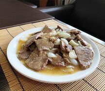 Говядина, тушенная в соусе с луком